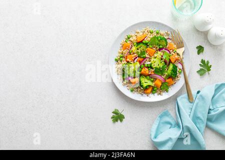 Insalata calda vegetariana di quinoa e broccoli con zucca o zucca al forno, piselli verdi e cipolla rossa fresca. Vista dall'alto Foto Stock