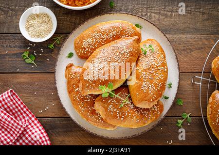 Torte fatte in casa o polpettine farciti con cavolo su sfondo di legno. Vista dall'alto Foto Stock