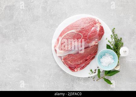 Filetto di carne di vitello crudo sul tagliere della cucina con ingredienti per cucinare, vista dall'alto, in testa, piatto Foto Stock