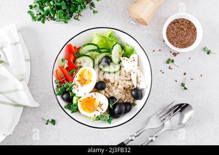 Farinata d'avena salata di ispirazione greca con cetriolo fresco, peperone, olive, lattuga, formaggio feta, germogli di rafano e uova sode per una colazione sana Foto Stock