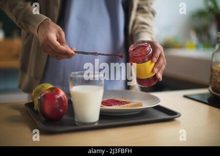 Primo piano dell'operatore sanitario che prepara la colazione in casa di cura per gli anziani. Foto Stock