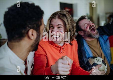 Felici tifosi tedeschi amici che guardano il calcio a casa e festeggiano. Foto Stock