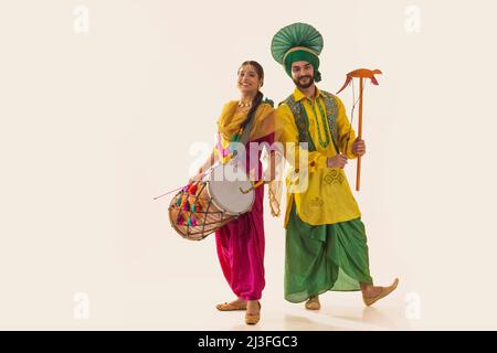 La coppia Sikh si esibisce in bhangra con tamburo e kato durante la celebrazione di Baisakhi Foto Stock