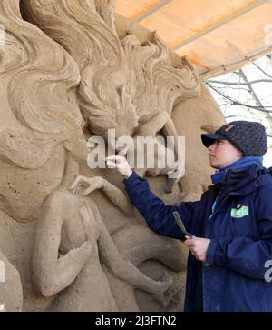 08 aprile 2022, Meclemburgo-Pomerania occidentale, Warnemünde: Nella mostra di sculture di sabbia 'Warnemünder Sandwelt' Susanne Ruseler (Paesi Bassi) lavora sulla sua scultura 'la Sirenetta'. Quattro artisti provenienti da quattro paesi trasformano 300 tonnellate di sabbia in uno spettacolo all'aperto sul tema "Fairy Tales of the Sea", che si apre il 11.04.2022. Foto: Bernd Wüstneck/dpa Foto Stock