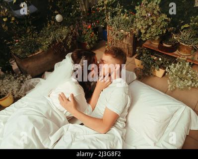 una coppia di sposi si trova sul letto dell'hotel e si rilassa insieme. uomo e donna in accappatoi hanno riposo, tempo libero, piacere. effetto grano Foto Stock