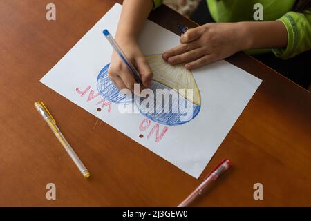 Le mani di un bambino disegnano un'icona a forma di cuore con l'immagine della bandiera nazionale dell'Ucraina. Vista dall'alto. Bambini contro la guerra. Bambini Foto Stock