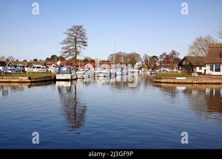 Una diga sul fiume Bure a bordo di un cantiere con gli incrociatori ormeggiati sui Norfolk Broads a Horning, Norfolk, Inghilterra, Regno Unito. Foto Stock