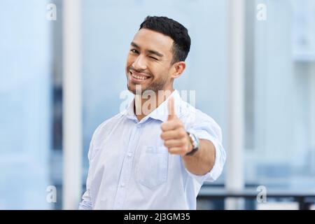 Hai fatto la scelta giusta scegliendo il mio business. Colpo di un bel giovane uomo d'affari in piedi da solo in ufficio e facendo un pollice su gesto. Foto Stock