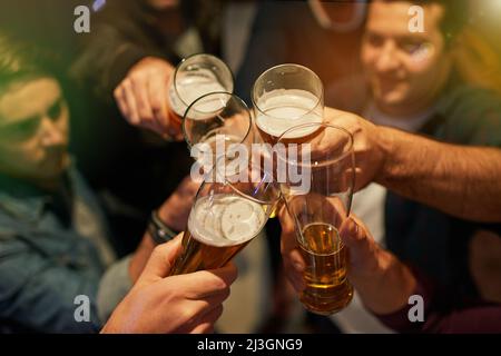 Ragazzi notte. Shot ad angolo alto di ragazzi che tostano con birre a una festa. Foto Stock