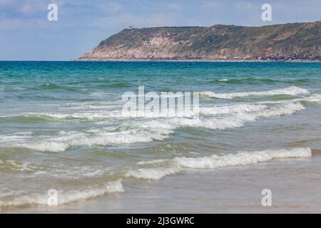 Francia, Manica, Cotentin, Sciotot Cove, tra Les Pieux e le Rozel, spiaggia di sabbia fine dorata, increspature, mare blu turchese e ristorante Semaphore a Capo Flamanville sullo sfondo Foto Stock