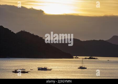 Filippine, Palawan, arcipelago delle Calamianes, Coron Town, tramonto sul mare e canoe contro la luce Foto Stock