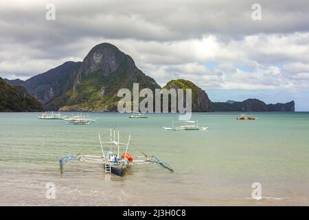 Filippine, Palawan, El Nido, canoe sulla spiaggia e isola rocciosa sullo sfondo Foto Stock