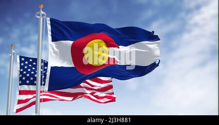 La bandiera dello stato del Colorado sventola insieme alla bandiera nazionale degli Stati Uniti d'America. Sullo sfondo c'è un cielo limpido. Foto Stock