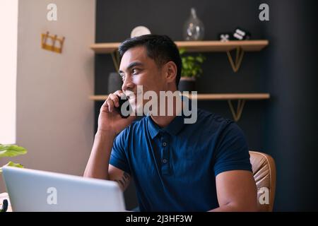 Un primo piano di un giovane uomo d'affari asiatico che prende una chiamata al suo ufficio scrivania Foto Stock