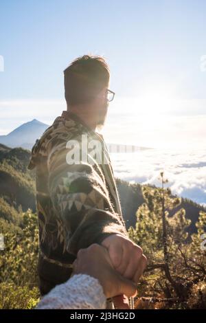 Coppia su una montagna, uomo che guarda l'orizzonte tenendo la mano della donna, concetto - viaggio, stile di vita, amore, libertà, natura, convivenza Foto Stock