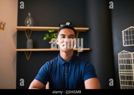 Un ritratto di un giovane uomo d'affari asiatico seduto in ufficio sorridente Foto Stock