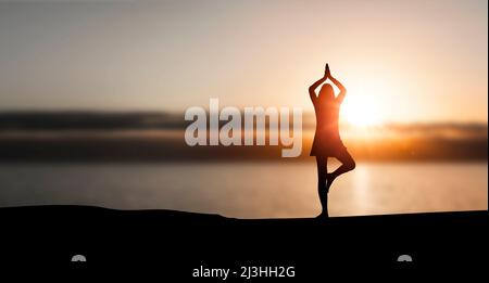 Silhouette di donna che fa yoga sulla spiaggia Foto Stock