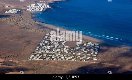 Isole Canarie, Lanzarote, isola vulcanica, costa nord-occidentale, eremo, chiesa, Ermita de las Nieves, azzurro cielo, vista dall'Ermita fino alla costa occidentale di un insediamento turistico quasi quadrato di molte case bianche, di fronte spiaggia, blu mare Foto Stock