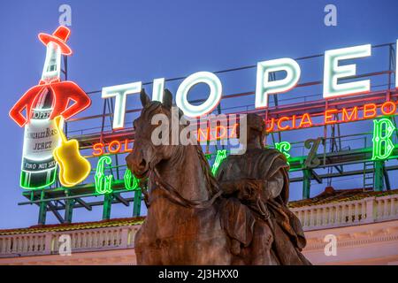 Il famoso cartello pubblicitario Tio Pepe si erge su una statua di re Carlo III, nella Puerta del Sol, nel centro di Madrid, Spagna. Foto Stock