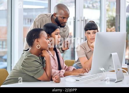 Tutti si sforzano di raggiungere un unico obiettivo unificato. Foto di un gruppo di uomini d'affari che parlano di qualcosa su un desktop. Foto Stock