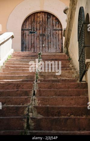 Scala ben consumata che si affaccia su una porta ad arco in legno nella città vecchia di Palma de Mallorca, Spagna Foto Stock