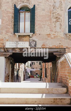 Vista su un ponte veneziano in uno stretto vicolo nel quartiere Castello di Venezia, Italia Foto Stock