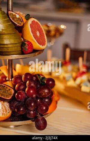 Assortimento di frutta tropicale su un piatto bianco con succo fresco, sfondo tessile grigio. Vista dall'alto. Foto Stock