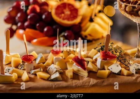 Formaggi assortiti su tavola di legno, noci, uva, pane su sfondo di pietra grigia, vista dall'alto, piatto, spazio copia Foto Stock