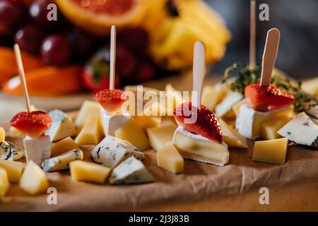 Canapes assortimento di cibo e dessert su piatti. Ciliegie d'uva con formaggio e gamberi con salsa, fragole con menta e marmellata in coppe, deliziosa FIS Foto Stock