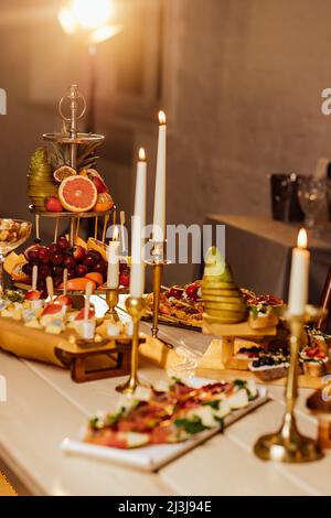 Nel cortile della villa in Toscana si trova una tavola in legno per banchetti decorata con composizioni di cotone ed eucalipto, bicchieri, candele e piatti a Foto Stock