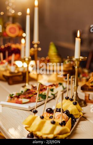 Pasto. Tavolo buffet festivo per gli ospiti. Assortimento di salumi, tartine su spiedini di legno, spuntini natalizi con frutta e insalate. Ricevimento nella parte Foto Stock