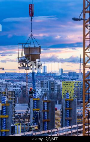 Vienna, cantiere di alta casa di appartamenti, gru, secchio di cemento o benna di gru, cementazione, operaio di costruzioni, progetto 'Danube Flats', skyline di Vienna, fiery tramonto nel distretto 22. Donaustadt, Austria Foto Stock