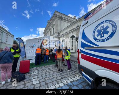 Przemysl, Polonia. 8th Apr 2022. Un'ambulanza è parcheggiata fuori dalla stazione ferroviaria di Przemysl e la tenda World Central Kitchen, ion la vecchia strada acciottolata, n caso di emergenze, come la salute di molti ucraini è povera dopo aver sofferto condizioni terribili a causa della guerra. I volontari nei giubbotti rossi preparano i pasti, buttano fuori i rifiuti e parlano con i rifugiati. Background: Centinaia di rifugiati che sono appena sfuggiti al terrore di Putin in Ucraina arrivano in Polonia alla stazione ferroviaria di Przemysl oggi, e hanno una deliziosa colazione di stufato di manzo e salame e sandwich al formaggio presso il World Central Foto Stock