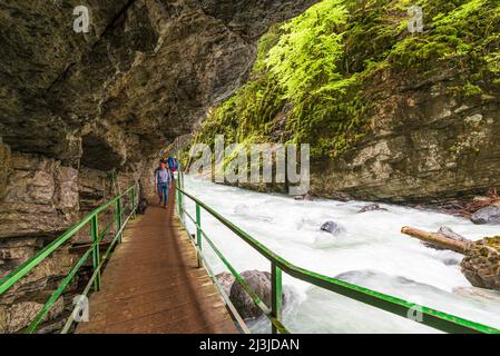 Una persona cammina su un ponte pedonale di legno attraverso la gola di Breitachklamm Foto Stock