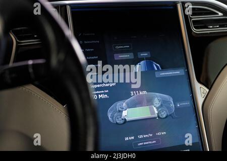 Vista interna dell'auto durante la ricarica presso una stazione Supercharger Tesla in Germania. Foto Stock