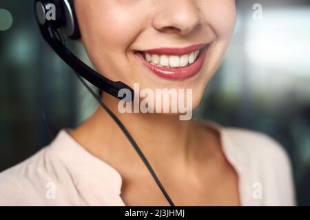 Shes in piedi vicino per prendere la vostra chiamata. Scatto ritagliato di un giovane agente del call center che lavora in ufficio. Foto Stock