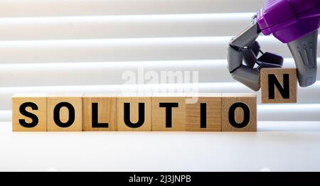 Parola di soluzione scritta sul blocco di legno. La parola di soluzione è fatta di blocchi di legno che giacciono sul tavolo giallo. Soluzione, concetto aziendale, bac giallo Foto Stock