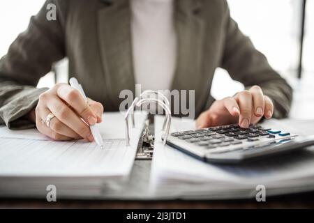 Primo piano della mano di un contabile che calcola sul posto di lavoro. Foto Stock