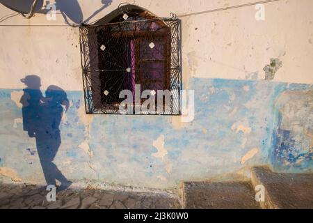 Le ombre di un bambino e del suo custode sono visibili su un muro; Chefchaouen, Marocco Foto Stock