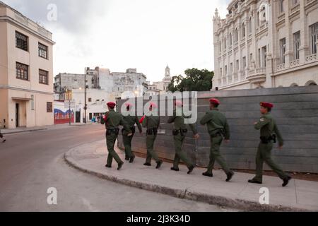 Diversi soldati camminano in formazione mentre trasportano una bandiera cubana attraverso le strade del centro di l'Avana, Cuba; l'Avana, Cuba Foto Stock