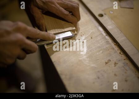 Il falegname taglia l'albero. Master lavora con l'utensile sul legno. Crea giunto. Lavorazione del materiale. Foto Stock