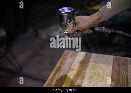 Verniciatura a bordo. Il carrello bullet è in funzione. Consente di tenere lo strumento a mano. La macchia è applicata all'albero. Foto Stock