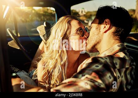 Questo viaggio ci ha reso profondamente connessi l'uno con l'altro. Colpo di una coppia affettuosa baciare in un pick-up camion. Foto Stock