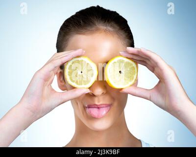 Quando la vita ti dà limoni, pucker in su. Scatto di una giovane donna cosciente della salute che posa con i limoni sopra i suoi occhi in studio. Foto Stock