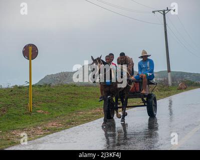 Uomini cubani che cavalcano su un carro a cavallo durante una tempesta di pioggia a Trinidad, Cuba. Foto Stock