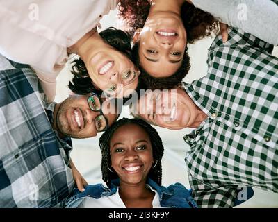 Abbraccia la tua competenza. Shot di un team di creativi accoccolati insieme nell'unità. Foto Stock