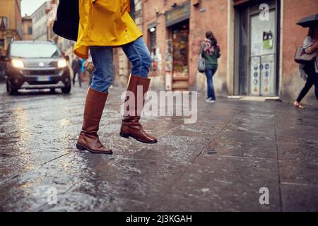 Primo piano di gambe di una giovane ragazza che cammina sulla pioggia in città in modo fretta. Passeggiata, pioggia, città Foto Stock