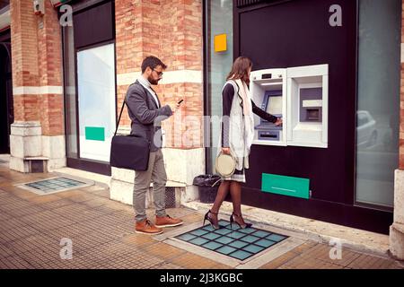 Business Woman inserire carta di credito in plastica in strada bancomat banca per prelevare denaro Foto Stock