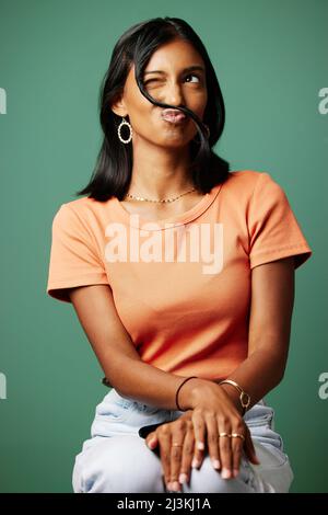 È bello lasciarsi andare. Scatto di una donna che fa un colpo divertente volto contro uno sfondo studio. Foto Stock