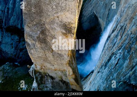 Un arrampicatore sulla parte inferiore della guglia della freccia perduta appesa sopra le cascate di Yosemite. Foto Stock